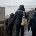Que faire pendant les vacances de la Toussaint en Normandie : famille sur la jetée d’Arromanches sous la pluie